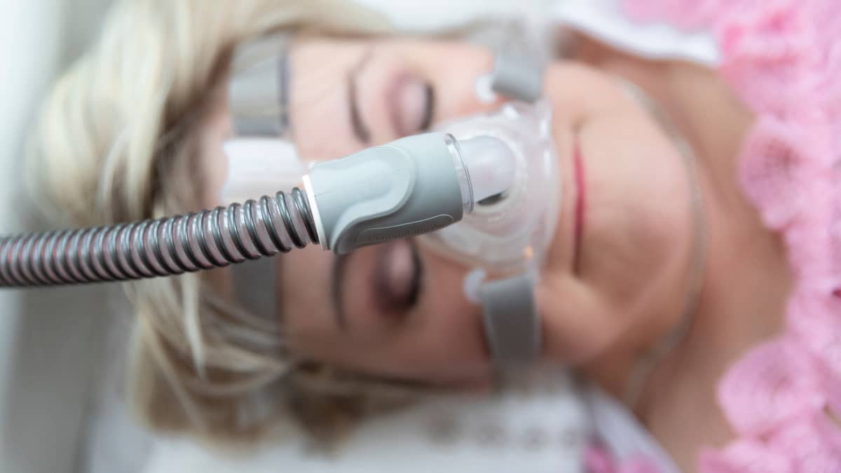 CPAP ylipainehengityslaiteen maski naisen kasvoilla.
