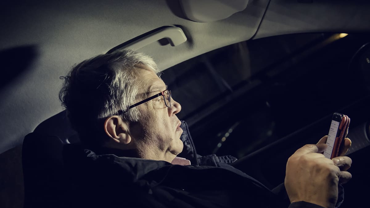 Juha Rehula istuu autossa pimeyden keskellä tutkien puhelintaan.