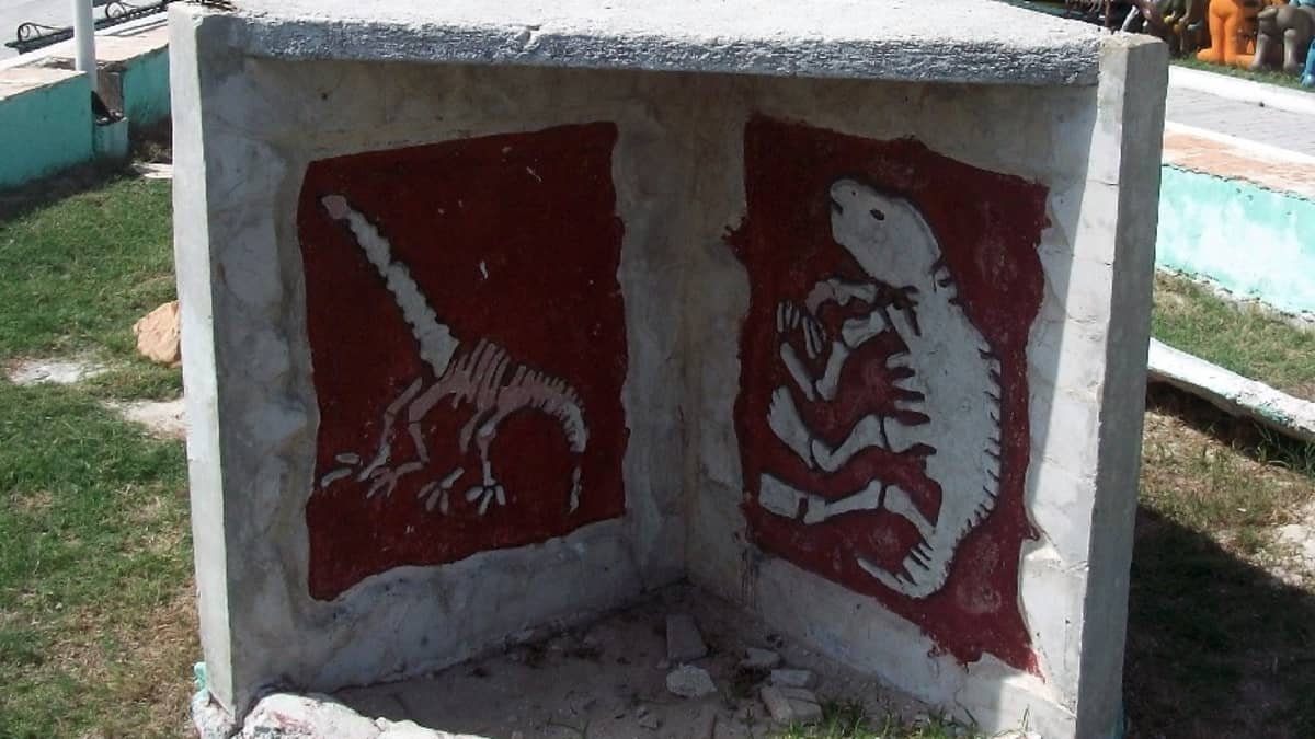 Betoninen muistomerkki, johon on maalattu kahden dinosauruksen luurangot.
