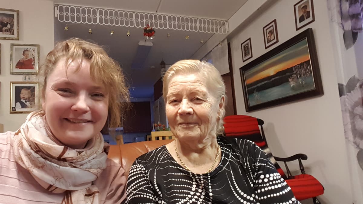 Nainen selfiessä vieressä istuvan eläkeläismummon kanssa.