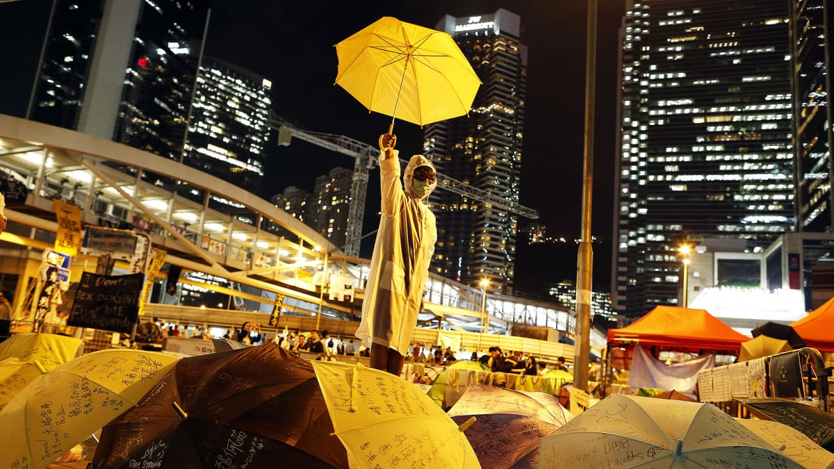 Mielenosoittaja pitelee keltaista sateenvarjoa.