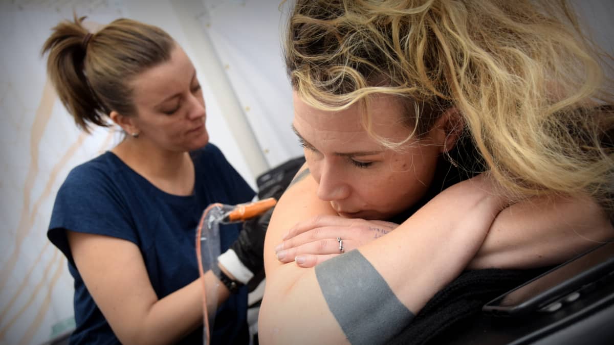 Säde Sonck tatuoi Jenni Ahtiaisen selkää