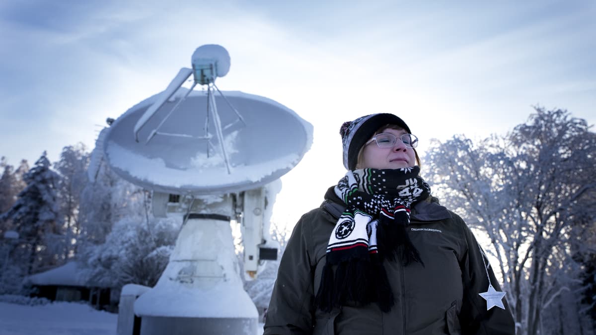 Päivikki Puolakka seisoo radioteleskoopin edessä silmät kiinni.