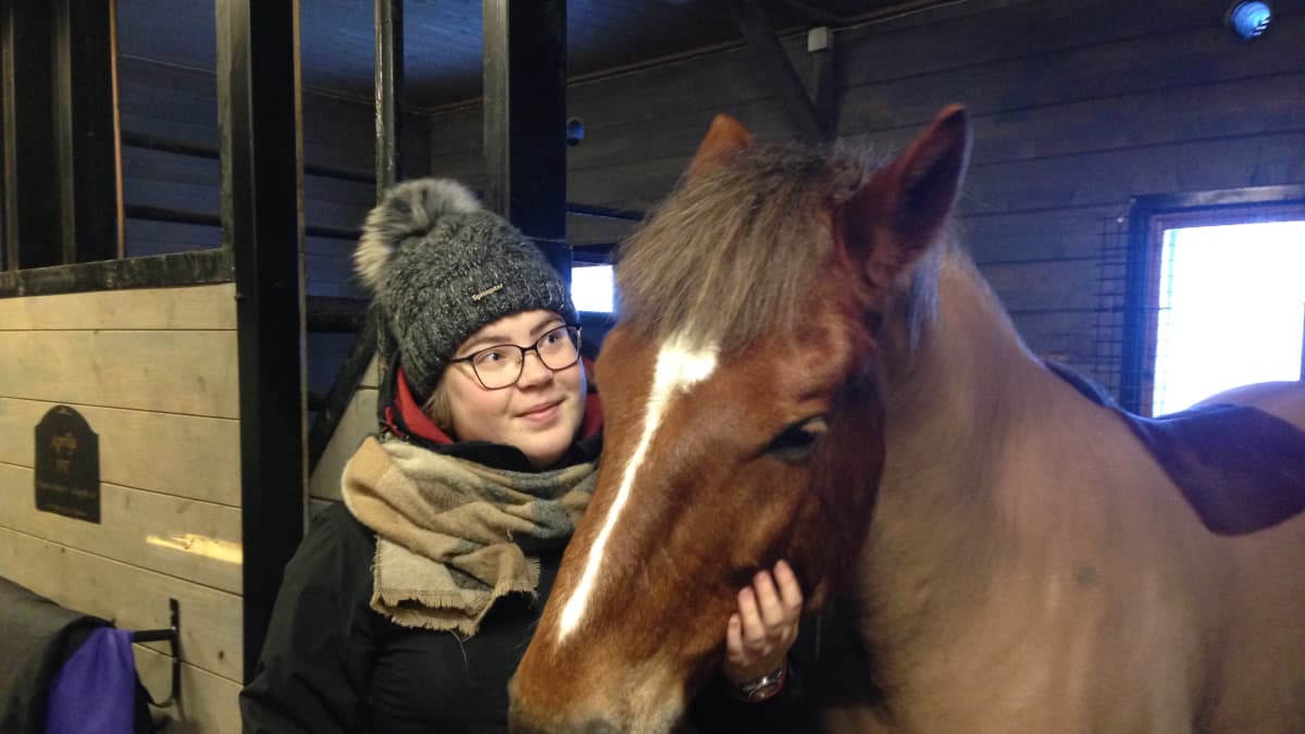 Janina Tiihonen hevosen kanssa tallissa