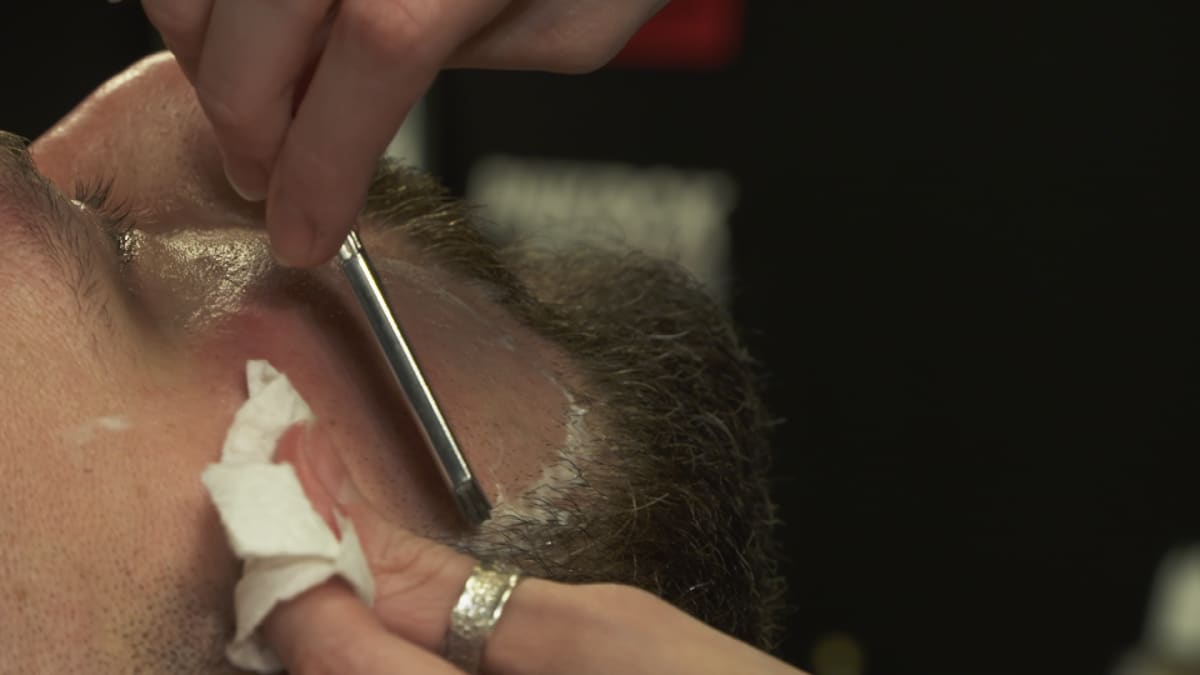 Tiina Sarja ajaa partaa partaveitsellä, jossa on kertakäyttöinen terä hygieniasyistä.