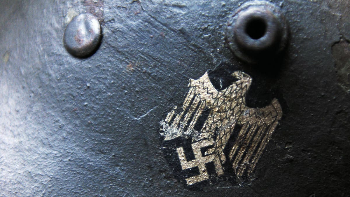 Mustassa sotilaskypärässä on ns. Parteiadler, natsipuolueen symboli. Symbolissa kotka seisoo hakaristin päällä.