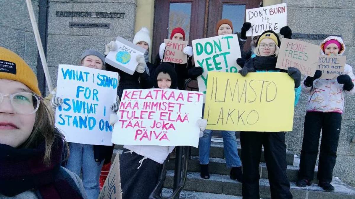 Nuoria Joensuun kaupungintalon portailla banderollien kanssa. 
