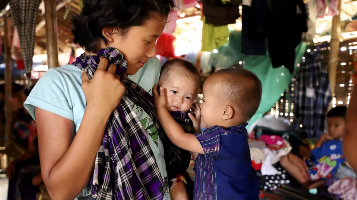 Naisen pitämä pikkuvauva kiinnosti toista lasta väliaikaisella pakolaisleirillä Myitkyinassa Kachinin osavaltiossa toukokuussa 2018. Pakolaisten heikot olot tekevät heistä helposti alttiin saaliin ihmissalakuljettajille. 