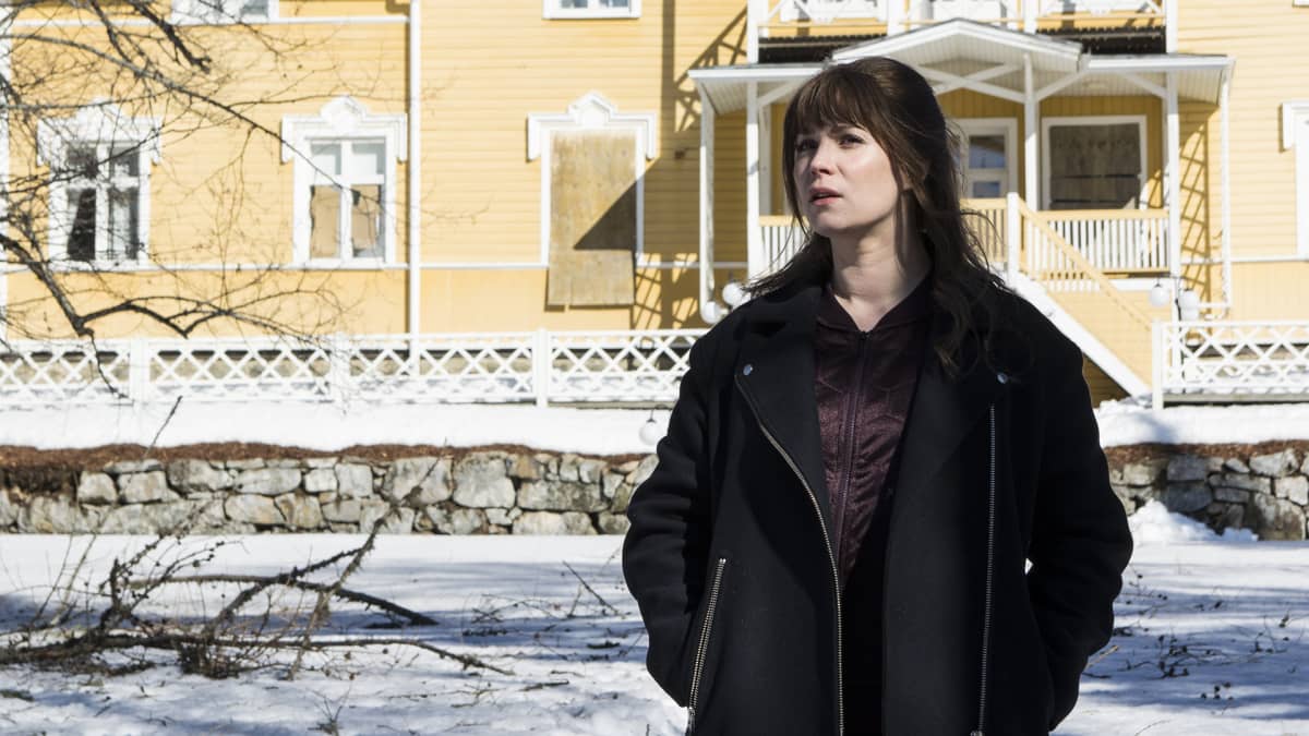 Näyttelijä Pihla Viitala televisiosarjan kuvauksissa vanhan kartanon lumisella pihalla.