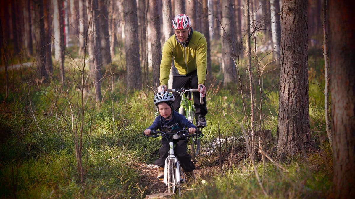 Isä ja poika pyöräilemässä metsässä