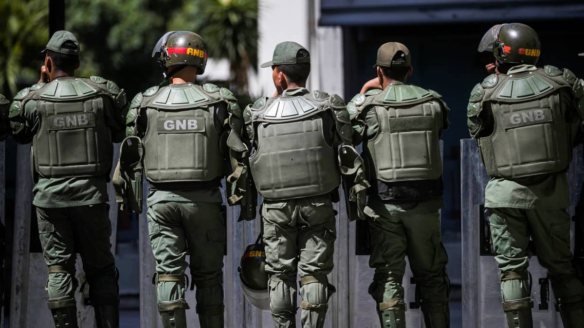 Koira lepää maassa taustallaan Venezuelan GNB:n poliisvoimia.