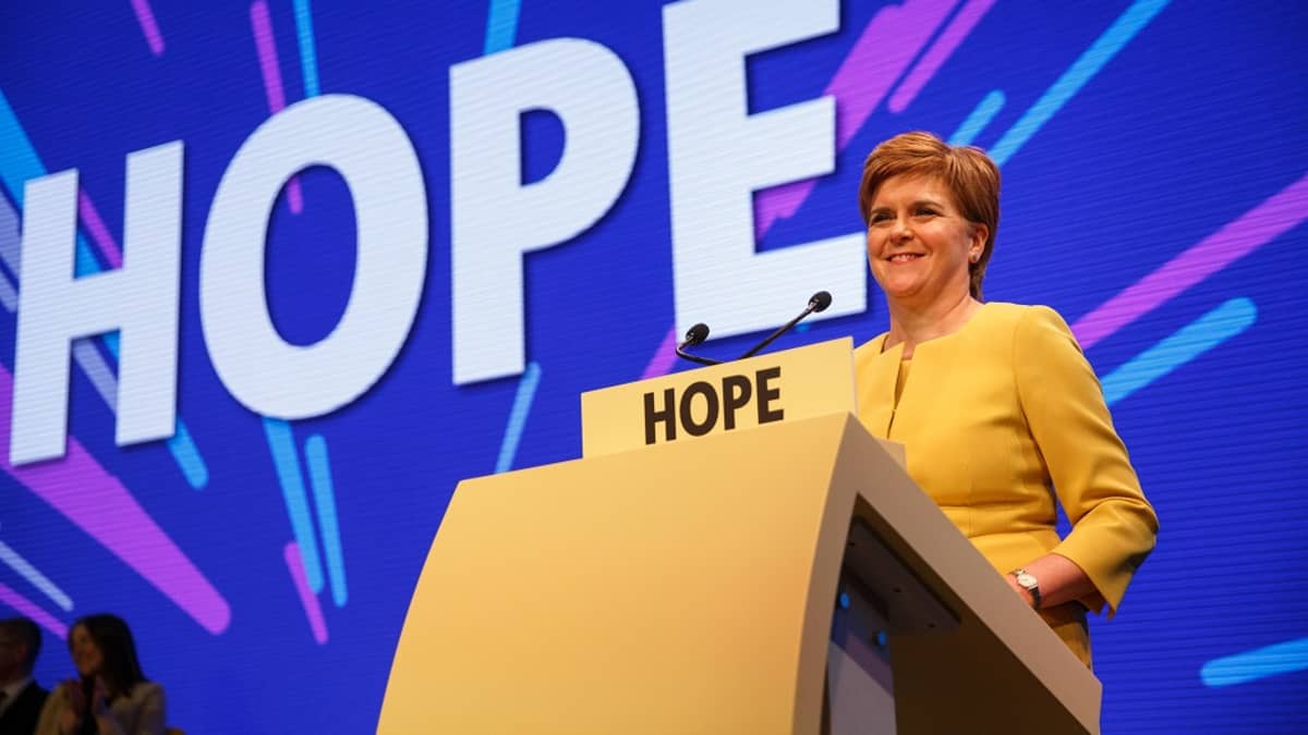 Kuvassa Skotlannin pääministeri Nicola Sturgeon lavalla puhujanpönton takana. Taustakankaalla lukee isoilla kirjaimilla teksti HOPE eli toivo. 