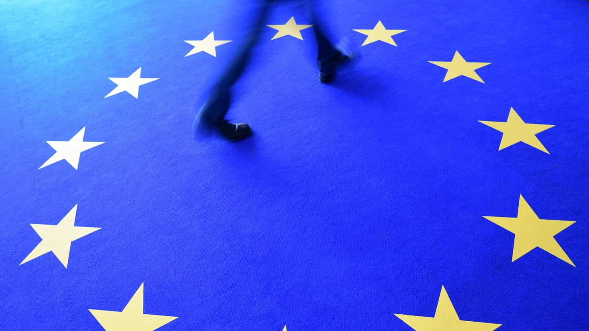 Mies kävelee matolla jossa on EU-lipun tähdet.