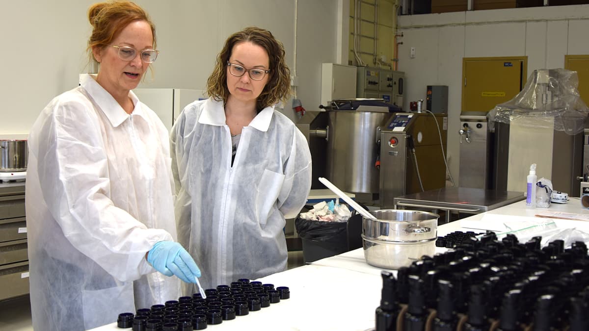 Kaksi naista tarkastelee poskiväriä luonnonkosmetiikkayrityksen tuotantotiloissa