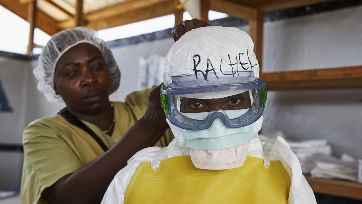Kuvassa puetaan suojavarusteita hoitajan päälle Benin kaupungissa. 