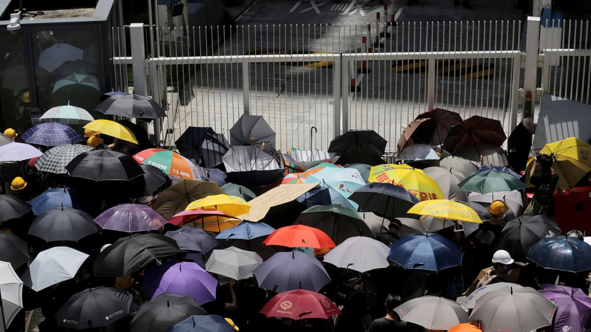 Demokratia-aktivistit ovat kokoontuneet sateenvarjojen kanssa hallintorakennuksen edustalle.