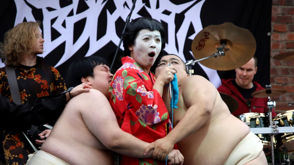 Japanin esityksessä kaksi sumopainijaa rutistaa neulovaa geishaa.