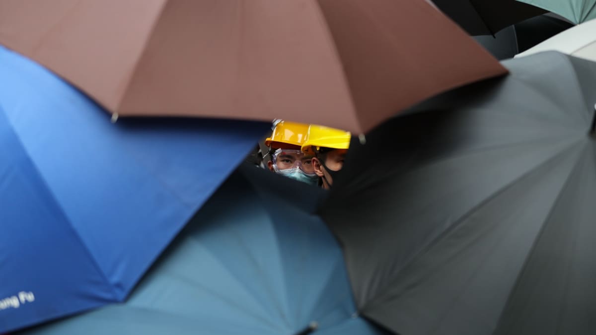Mielenosoittaja kurkistaa sateenvarjojen keskeltä.
