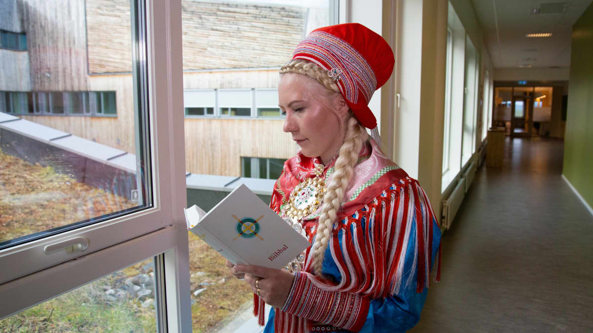 Nainen lukee pohjoissaameksi käännettyä Raamattua, Biibbalia.