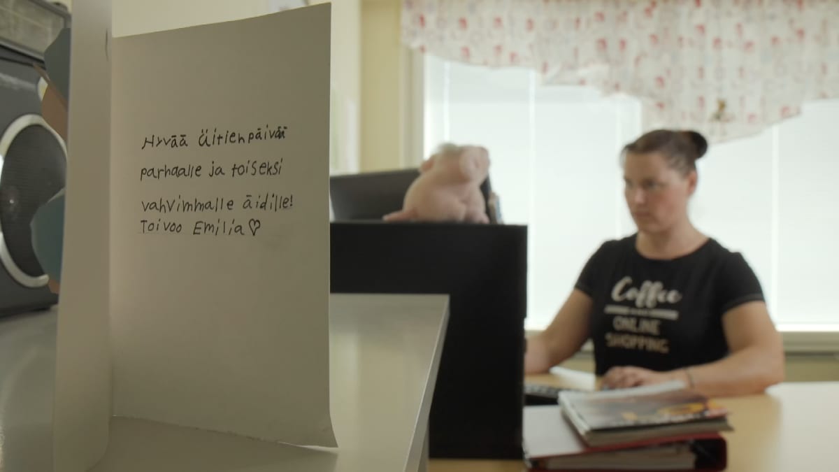 Suomen vahvin nainen 2018 Annika Eilmann istuu tietokoneella, etualalla tyttären Emilian tekemä äitienpäiväkortti.