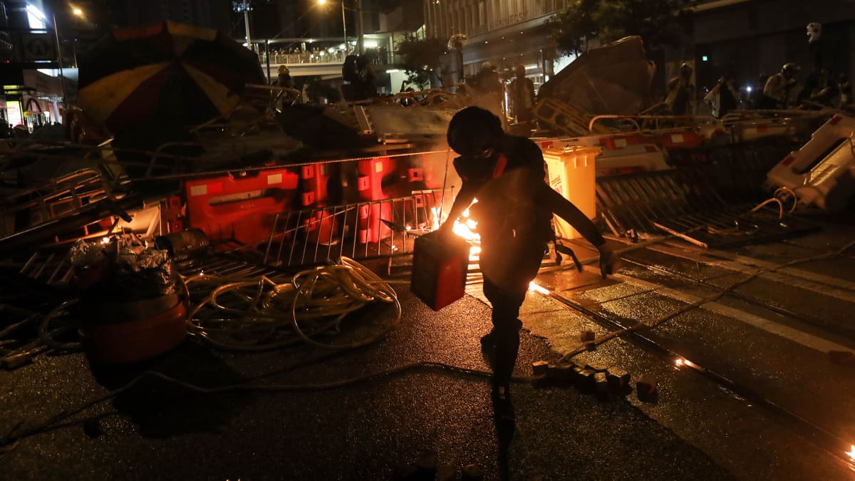 Mielenosoittaja kasaa barrikadia kadulla Hongkongissa.