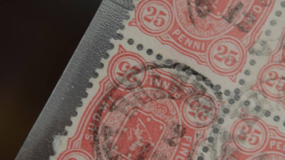 Lähikuva neljän punavalkoisen postimerkin ryhmästä, joista yksi postimerkki on väärinpäin