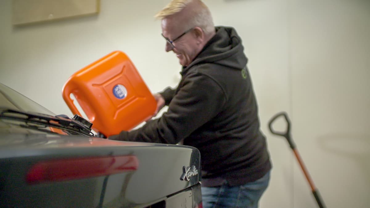 Vesa Vaine (eFlexFuelin Suomen myyntijohtaja) tankkaa oranssista kanisterista RE-85-polttoainetta vihreään Citroen Xantiaan eFlexFuel-asennuspisteessä Pirkkalassa.