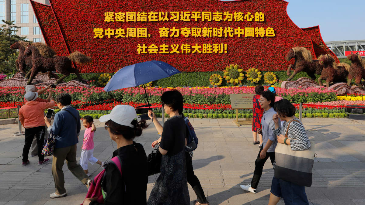 Kukilla koristeltu monumentti julistaa Xi Jinpingin ja kommunismin merkitystä juhlahumun alla Pekingissä.