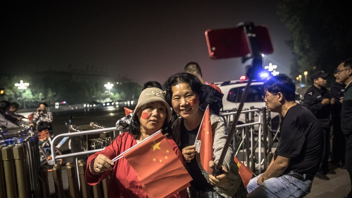 Naiset lipunnostoseremoniassa Pekingissä.