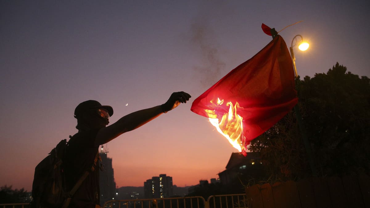 Mielenosoittaja sytyttää Kiinan lippua tuleen 1. lokakuuta Hongkongissa.