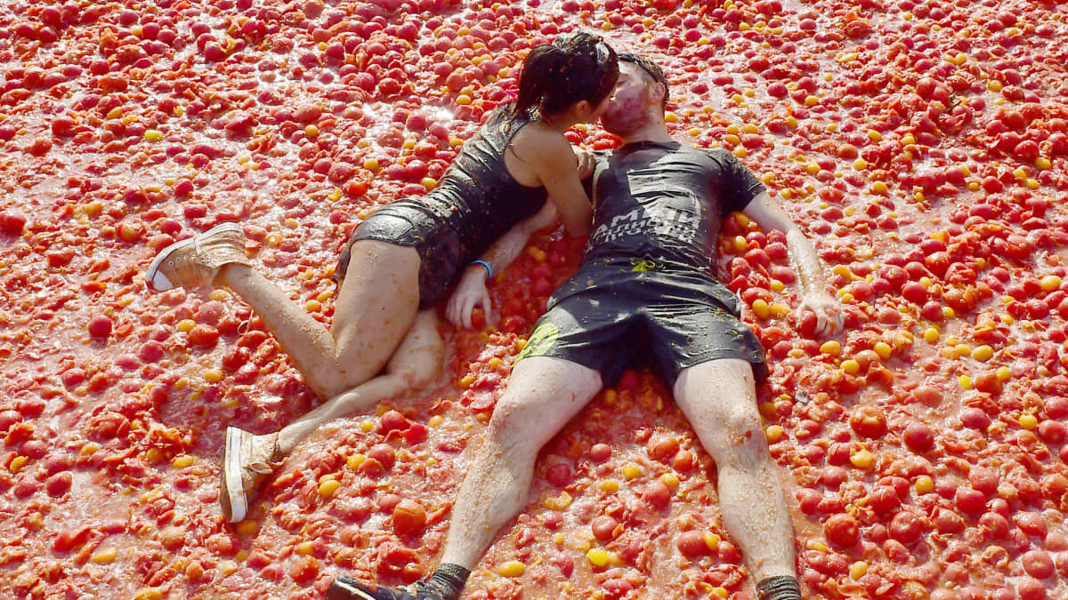 Pariskunta suutelee tomaattien päällä tomaattisota-festivaalilla Venäjällä.