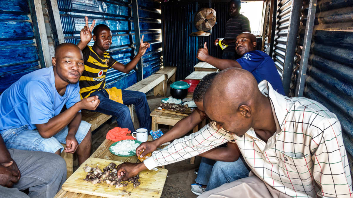 Miehet syövät lounasta  Etelä-Afrikassa.