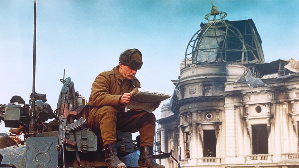 Sotilas istuu lukemassa sanomalehteä tankin kannella Bukarestissa.