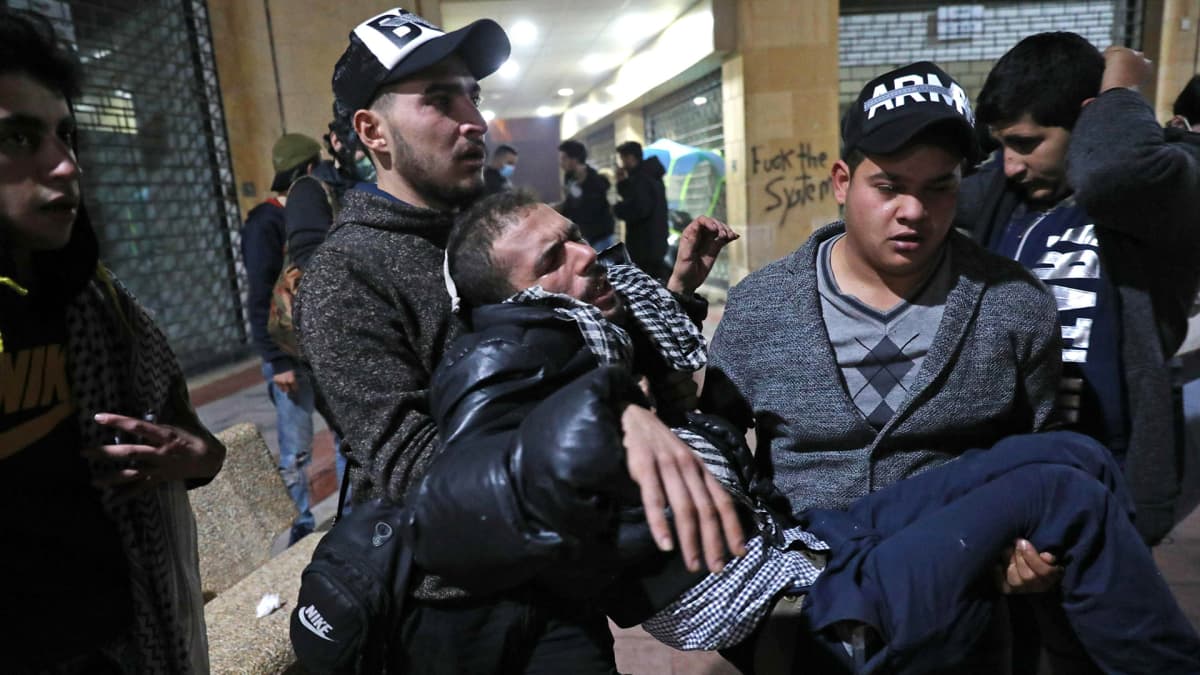 Kyynelkaasua hengittänyttä miestä kannettiin mielenosoituksessa Beirutissa 12. joulukuuta.