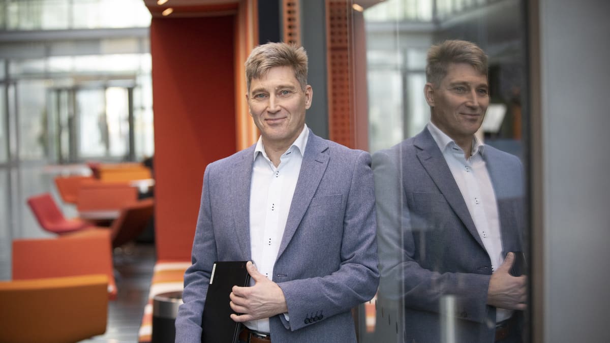 Johtava asiantuntija Timo Tuominen seisoo Finanssialan toimistorakennuksen vastaanottoaulassa kannettava tietokone käsissään.