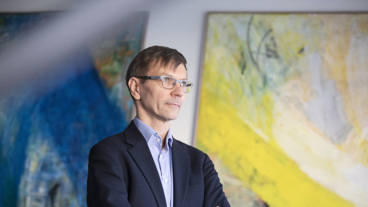 Verohallinnon kehittämisen asiantuntija Jukka Kyhäräinen seisoo kahden suuren maalauksen edessä ja katsoo ikkunan läpi kaukaisuuteen.