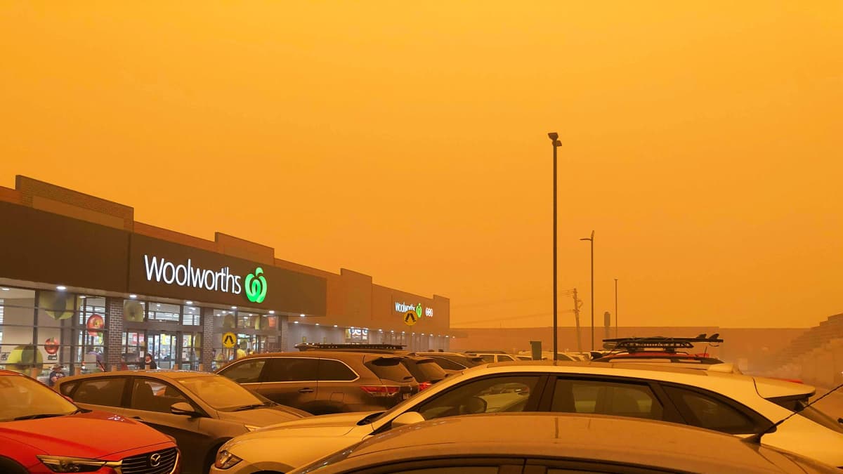 Keltaiseksi värjäytynt taivas supermarketin parkkipaikan taustalla.