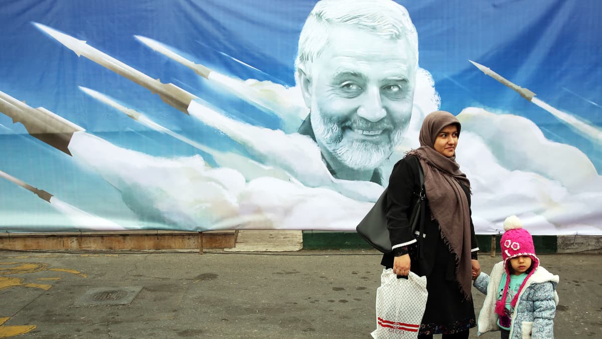 Nainen lapsensa kanssa käveli Quassim Suleimania esittävän julisteen ohi Teheranissa.