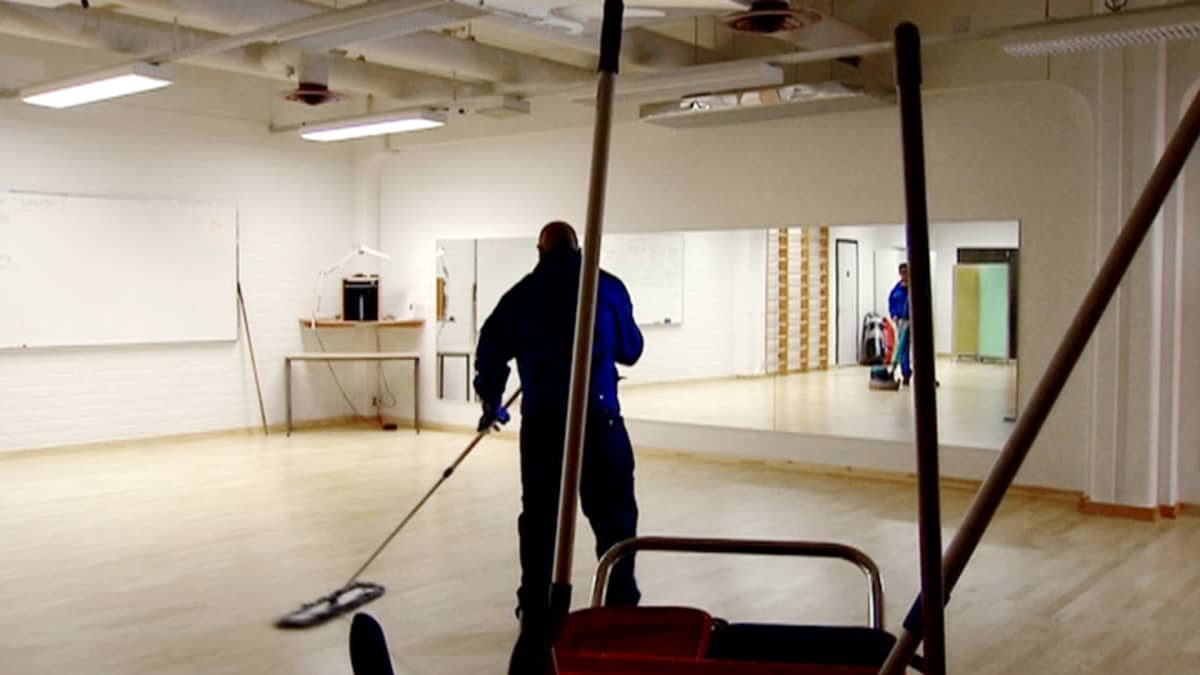 Siivoja moppaa lattioita yrityksen tiloissa.