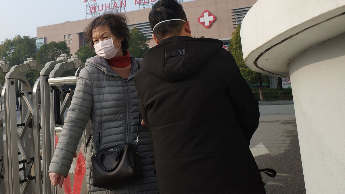 Terveysasema Wuhanissa ja hengityssuojaimella varustettu nainen