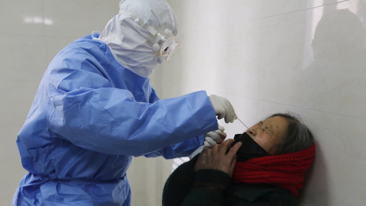 Lääkäri ottaa virustestin kuumeiselta potilaalta Kiinassa. 