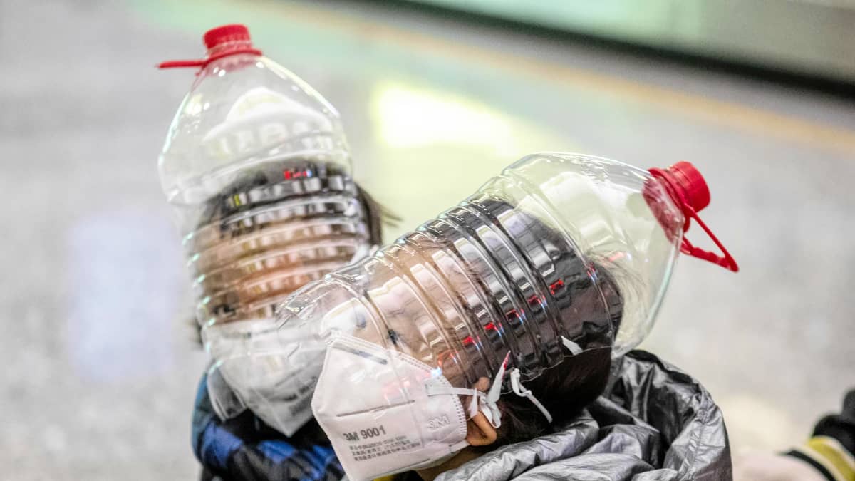 Suojamaskeilla ja muovisilla vesipulloilla peitetyt pikkupojat lastenvaunuissa lentoasemalla.