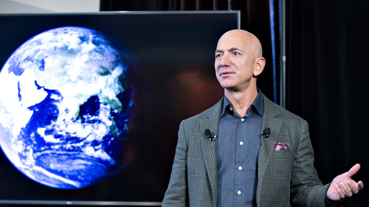 Jeff Bezos pitää puhettaan. Taustalla on maapallo kuvattuna avaruudesta.