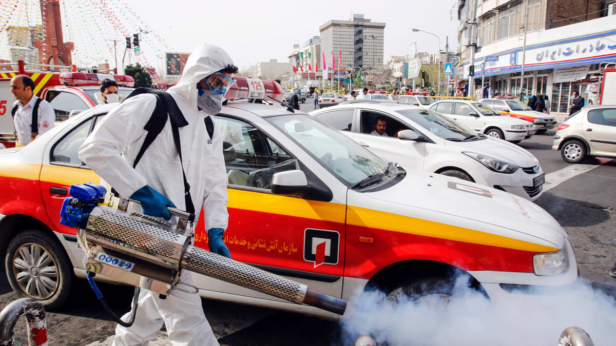 Palomies desinfioi katua Iranin pääkaupungissa Teheranissa perjantaina.