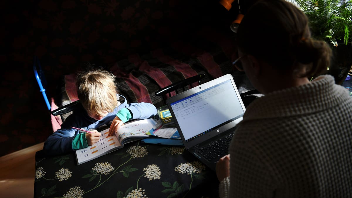 Koulusta kotiin jäänyt lapsi opiskelee yhdessä etätöitä tekevän äidin kanssa kotonaan Helsingissä tiistaina.