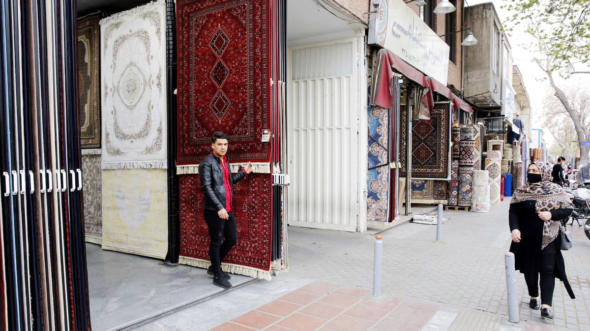 Iranialainen mattokauppias seisoo mattokaupan edustalla Teheranissa.