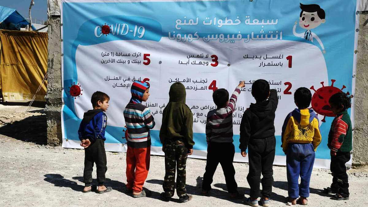 Syyrialaislapset tutkivat sunnuntaina 22. maaliskuuta pakolaisleirillä julistetta.