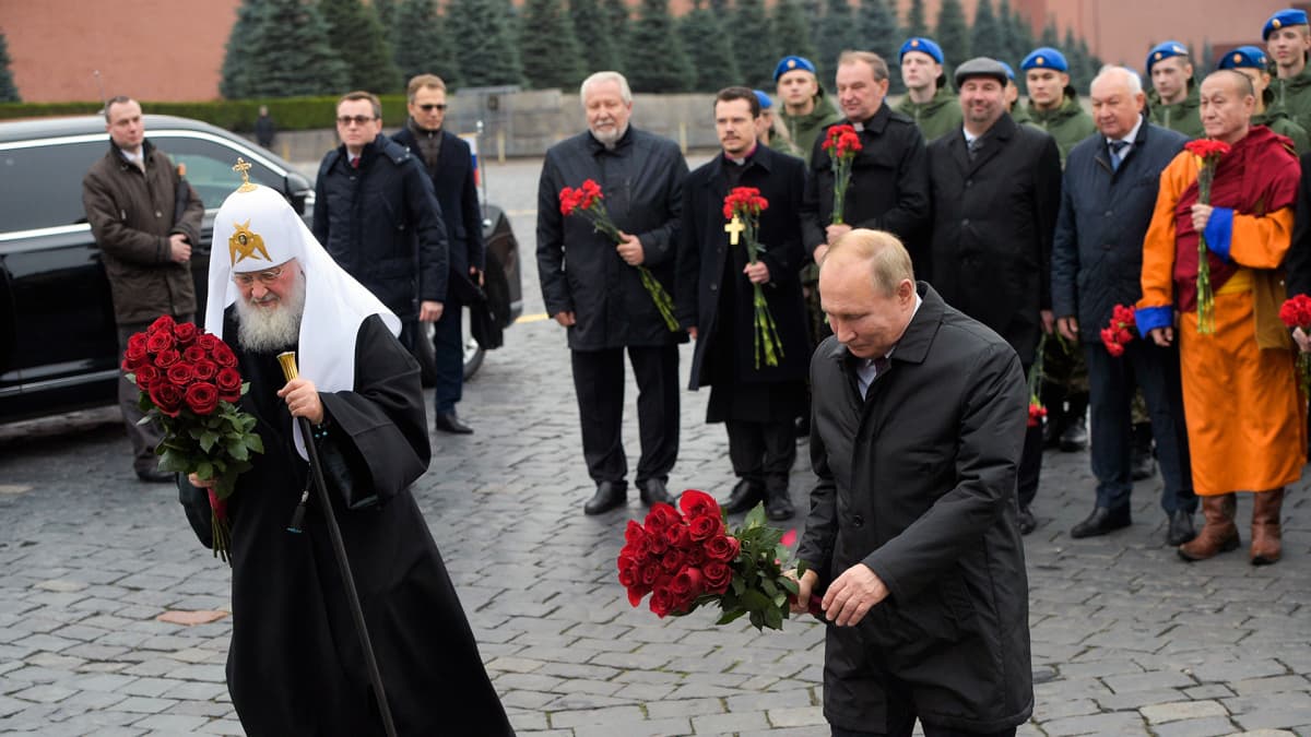 Kuvassa Venäjän ortodoksisen kirkon johtaja patriarkka Kirillja presidentti Vladimir Putin. Molemmilla on käsissään kukkakimput.