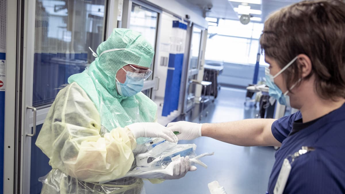 Suojapukuun pukeutunut hoitaja ja avustava hoitaja koronapotilaiden testaamiseen ja hoitoon tarkoitetulla osastolla Turun yliopistollisessa keskussairaalassa Tyksissä.