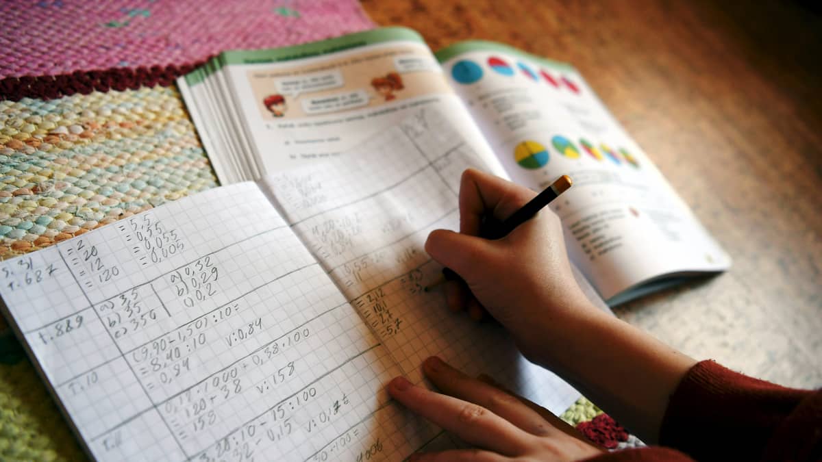 Kuvassa koululainen tekee matematiikan tehtäviä kotonaan.